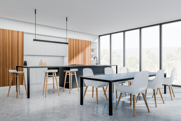 Light kitchen interior with seats and dining table, wooden shelves and window