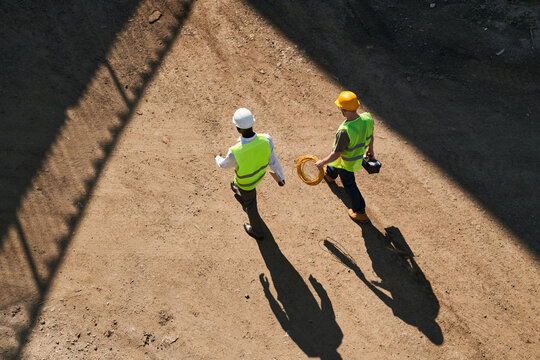 Directly above view of builders in hardhats and green waistcoats working at construction site