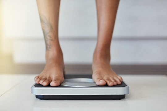 And the results are in. Closeup shot of a woman weighing herself on a scale at home.