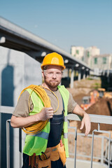 Portrait of young electrician with roll of cable standing at construction site