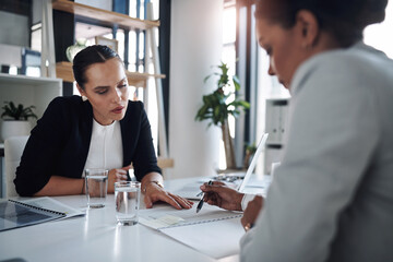 Lets first have a look at what the contract states. Cropped shot of two attractive young businesswomen filling out paperwork together inside an office.