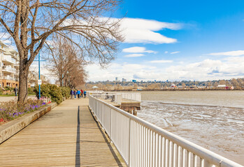 Pier and walkway by riverside. Sunny spring day in beautiful riverpark in New Westminster BC. Beautiful spring landscape