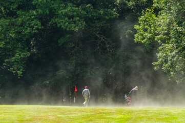 Golfspieler auf dampfendem Grün nach einem Gewitter über dem Golfplatz