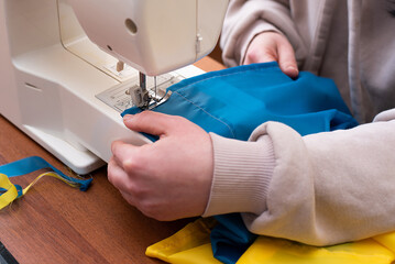 making flags of ukraine female hands fabric under the sewing machine