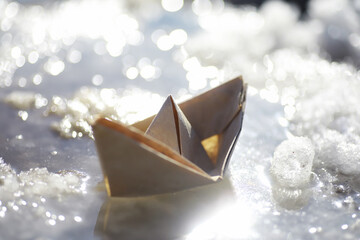 Paper boat in the water on the street. The concept of early spring. Melting snow and an origami...