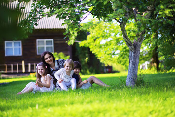 Young large family on a summer morning walk. Beautiful mother with children is playing in the park.