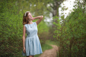 Fototapeta na wymiar Girl in blue dress in green park