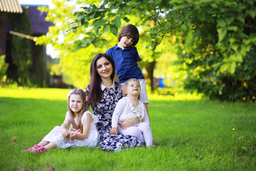 Fototapeta premium Young large family on a summer morning walk. Beautiful mother with children is playing in the park.