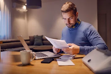 Fotobehang A casual businessman doing paperwork and working from home. © dusanpetkovic1