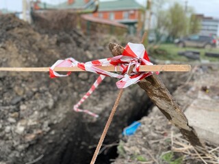 Signal tape tied up on the wooden beams and a deformed bar to warn about deep pit. Red and white...
