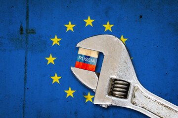 Flag of Russia on a wooden block, clamped with a wrench, against the background of the flag of the European Union. Sanctions. Country isolation. Economic blockade. Economic. Politics. - obrazy, fototapety, plakaty