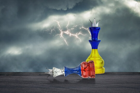 Chess Queen in the colors of the Flag of Ukraine, and a recumbent cracked chess queen in the colors of the Russian flag. Ukraine's victory over Russia in the war. Cloudy sky.