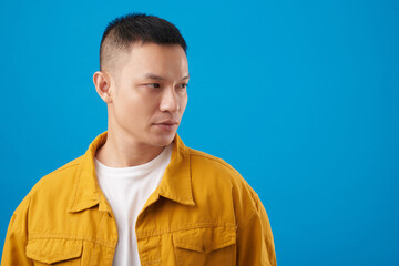 Portrait of serious young man in mustard denim jacket and white t-shirt looking away