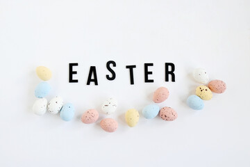 Flat lay non focus easter background with bouquet white flwoer and easter eggs in soft color on white background decorate and wooden black text , happy and funny season in april