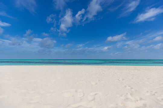 Closeup sandy beach waves and blue summer sky. Panoramic beach landscape. Empty tropical beach and seascape, horizon. Bright blue sky, soft sand, calmness, tranquil seaside relaxing sunlight, summer 