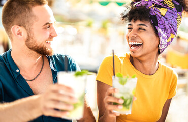 Multicultural trendy couple having fun drinking cocktails at beach party - Summer joy and life...