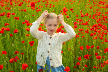 Little girl on the poppies meadow. Beautiful daughter on a poppy field outdoor. Poppies spring flowers.