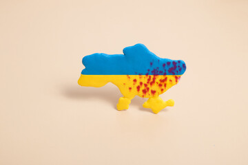Plasticine yellow and blue map of Ukraine with shots in the blood. War in Ukraine concept