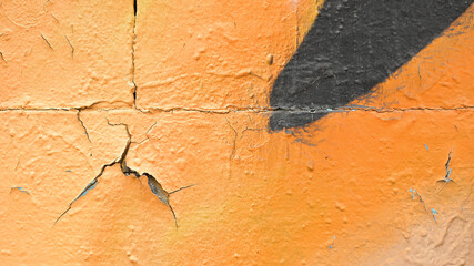 Orange wall with graffiti and cracks 