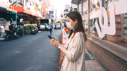 Business asian working woman wear face mask using mobile phone application for calling taxi transports