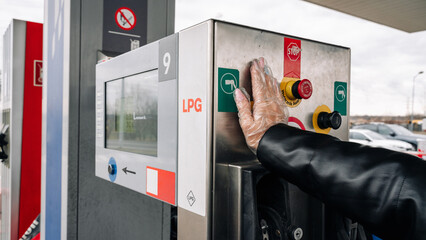 Person pumping gas. Fuel petrol for car at gasoline oil station nozzle in tank. Hand and black...