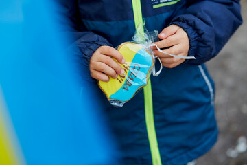 Patriotic little boy opening Ukrainian symbolic blue and yellow cookie. Stand with Ukraine. Support Ukraine. Stop russian aggression concept. Stop war in Ukraine. Pray for Ukraine.