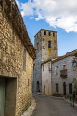 Fototapeta premium Clocher de l'Eglise Notre-Dame-de-l'Assomption depuis une ruelle du village médiéval des Matelles (Occitanie, France)