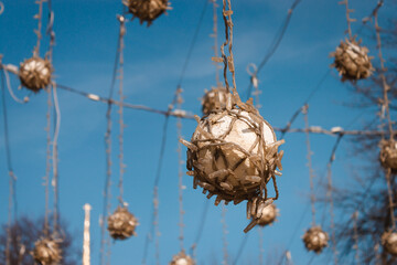 A closeup shot of a sphere covered with small light bulbs. It is hanging down from a wire in the street. Low angle shot during a sunny morning