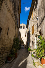 Fototapeta na wymiar Clocher de l'Eglise Notre-Dame-de-l'Assomption depuis une ruelle du village médiéval des Matelles (Occitanie, France)