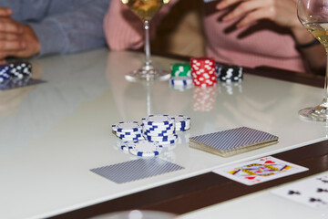 Naklejka premium Laying out cards on the table in poker game. Glass of champagne. Gambling concept. Candid moment. Poker background photography. Selective focus