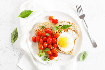 Healthy breakfast toast with fried egg and tomatoes.