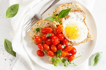 Healthy breakfast toast with fried egg and tomatoes.