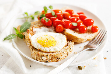 Healthy breakfast toast with fried egg and tomatoes.