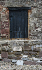 A black door within a granite wall 