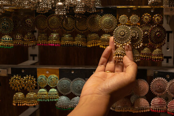 A hand of a woman selecting earrings on street market shop in Red fort, Delhi.