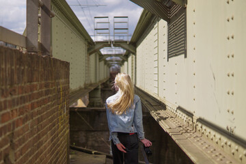 Model with blonde hair in between two metal plates of a railway with one point perspective