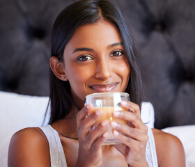 Its definitely a good morning. Shot of a young woman drinking a hot beverage while sitting on her bed. - obrazy, fototapety, plakaty