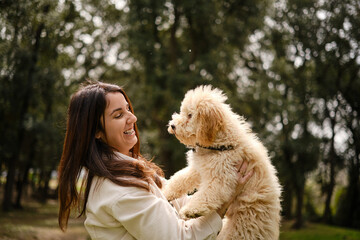 Happy woman holding her dog while enjoying a day outdoors in the nature.