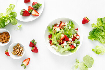 Strawberry and cottage cheese fresh fruit salad with walnut, almond and lettuce, top down view,...