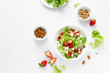 Strawberry and cottage cheese fresh fruit salad with walnut, almond and lettuce, top down view, flat lay