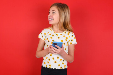 blonde little kid girl wearing daisy t-shirt red background holding in hands showing new cell