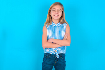 little kid girl with glasses wearing plaid shirt over blue background being happy smiling and...