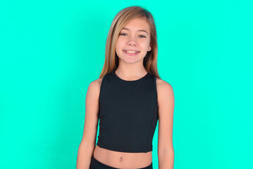 blonde little kid girl wearing black sport clothes over green background with nice beaming smile...