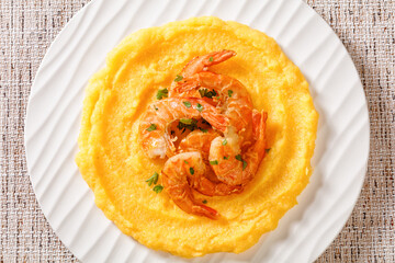 polenta with fried shrimps on plate, top view