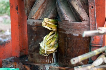 A picture of a sugarcane being crushed in a crusher and juice extracting out of it in India on a...