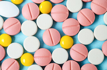 Many colorful pills macro on blue background.