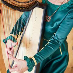 A woman in traditional celtic dress laying the celtic harp