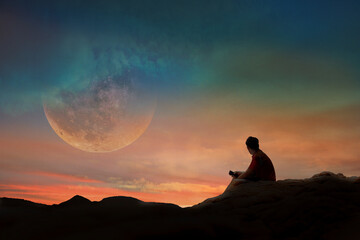 Young man is watching the full moon on a beautiful sunset.
