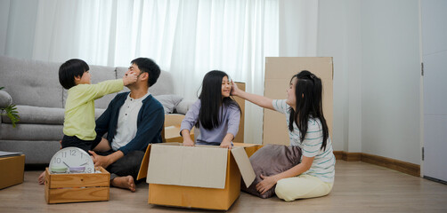 Smiling and laughing Asian family is happy in new home. Cute son and daughter help move things. Parents and children help to arrange things. family day activities together on moving day