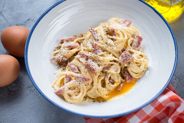Middle close-up of italian spaghetti carbonara served in a white plate, selective focus, studio shot